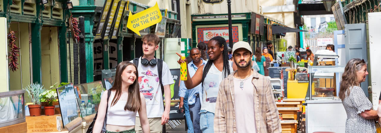 A group of students walking through the busy st nicks market 